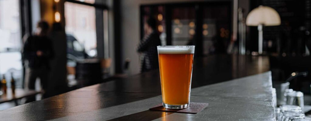 a pint glass of beer left alone at a bar