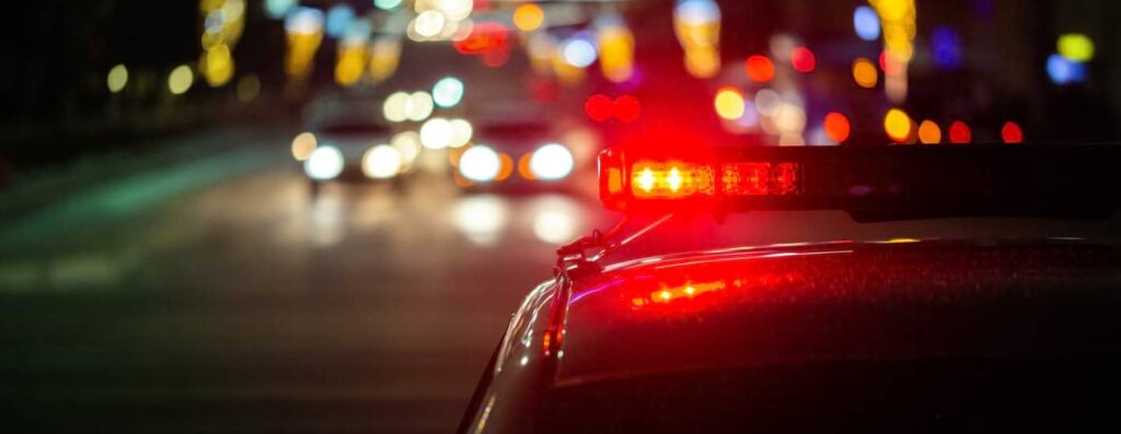 cop car with sirens on in traffic